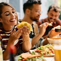 Woman smiling while eating lunch with friends at restaurant