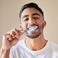 Man smiling while brushing his teeth